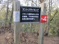 枯れ葉の落ちる道に立つ「マントクライミング」と書かれた看板の写真