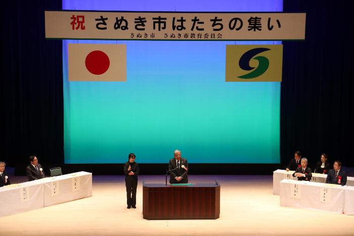 式典の壇上で市長が祝辞を述べている写真