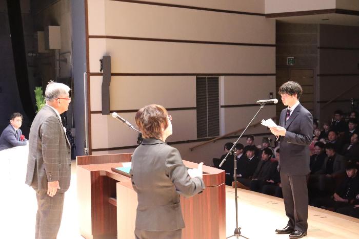 式典の壇上で代表者が宣誓を行っている写真