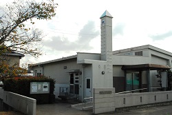 手前にスロープがあって細長い三角塔がある建物の写真