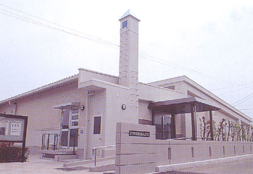 手前にスロープがあって細長い三角塔がある建物の写真