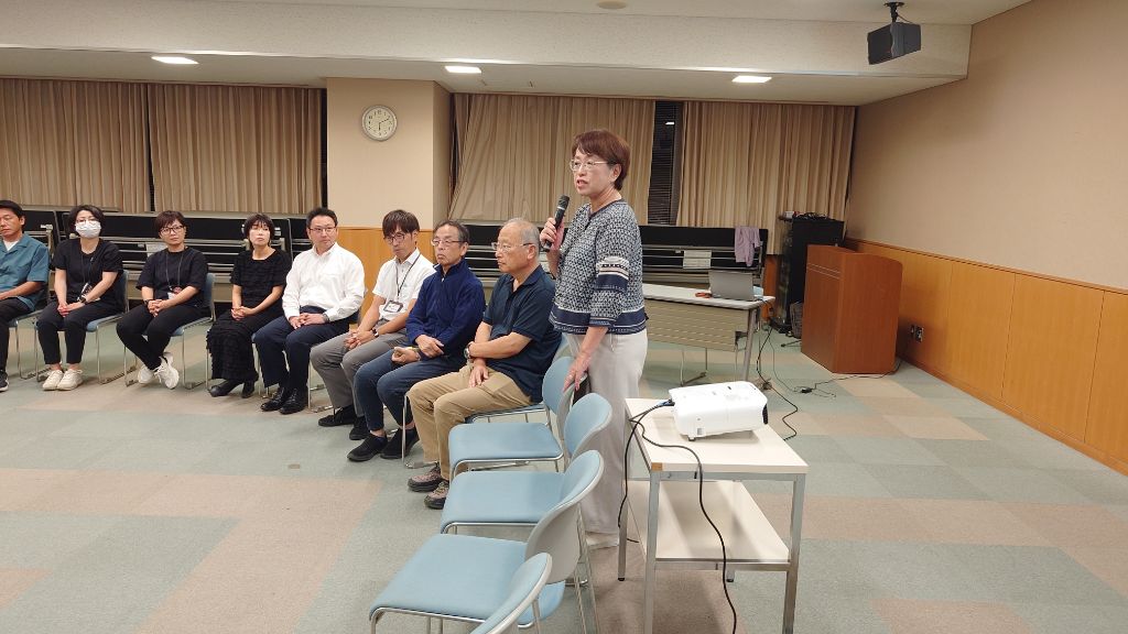 座っている参加者の前で女性がマイクを持って話している写真