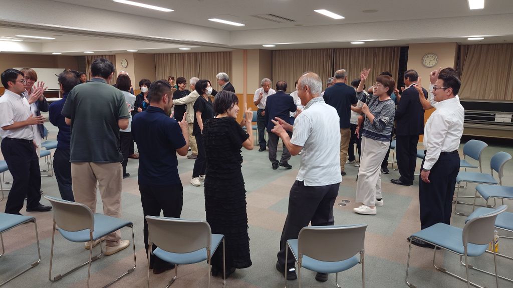 参加者たちが円になって立ち、手を動かしながら交流している場面の写真