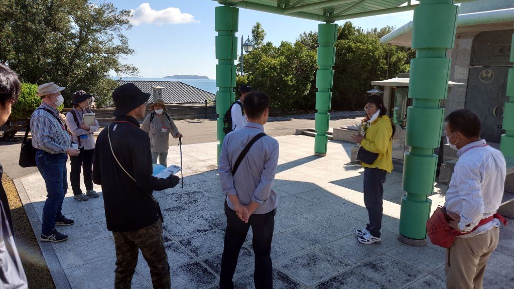 海沿いの施設でガイドの説明を聞く参加者たちの写真