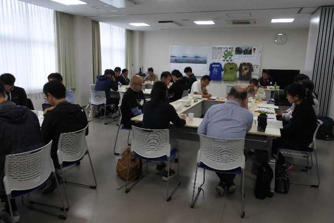 会議室で参加者たちがテーブルを囲んで食事をしている写真