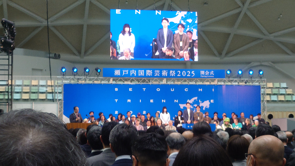 瀬戸内国際芸術祭2025開会式で、大型スクリーンの前に登壇者が並んでいる写真