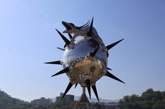 トゲ付きの球体の上にドラゴンが乗った屋外彫刻作品の写真