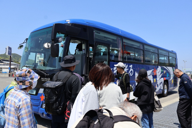 港で青い観光バスに乗り込む参加者の写真