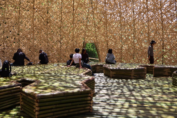 竹で組まれたドーム状のアート作品の中でくつろぐ来場者の写真