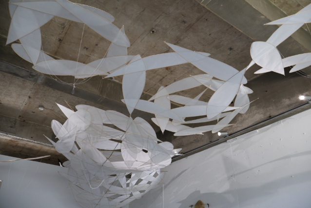 天井から白い帆のようなパーツが吊るされたアート作品の写真