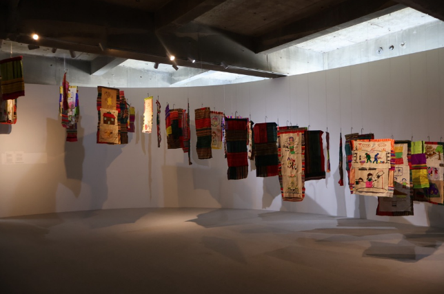 色とりどりの布作品が宙に吊るされたギャラリー展示の写真