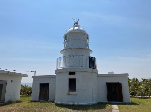青空の下に建つ白い灯台の外観写真