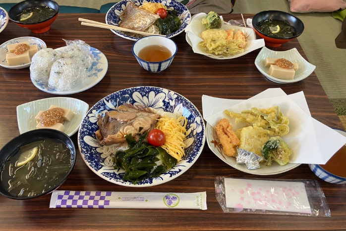 煮魚や天ぷら、小鉢が並んだ和食の定食がテーブルに並んでいる写真