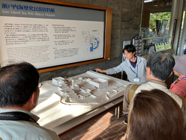 瀬戸内海歴史民俗資料館の模型を職員が参加者に説明している写真
