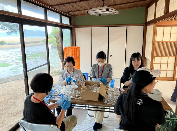 古民家の室内でレンズを磨くボランティアの女性たちの写真