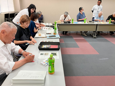 会議室の左側で机を囲んだ参加者たちが資料を広げてワークショップ作業に取り組んでいる写真