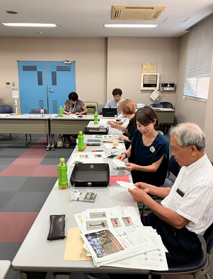 会議室の右側で資料を前にした参加者たちが折り紙を手にワークショップを楽しんでいる写真