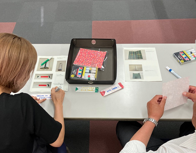 会議室の机の上で参加者がカラーペンや紙を使ってメッセージカードを作っている写真