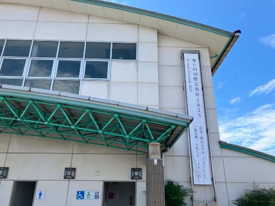 緑色のひさしが付いたホールの入口横に瀬戸内国際芸術祭の懸垂幕が掲げられている建物の写真