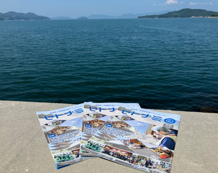 観光パンフレットを海辺の堤防の上に並べて背景に穏やかな海が広がっている写真