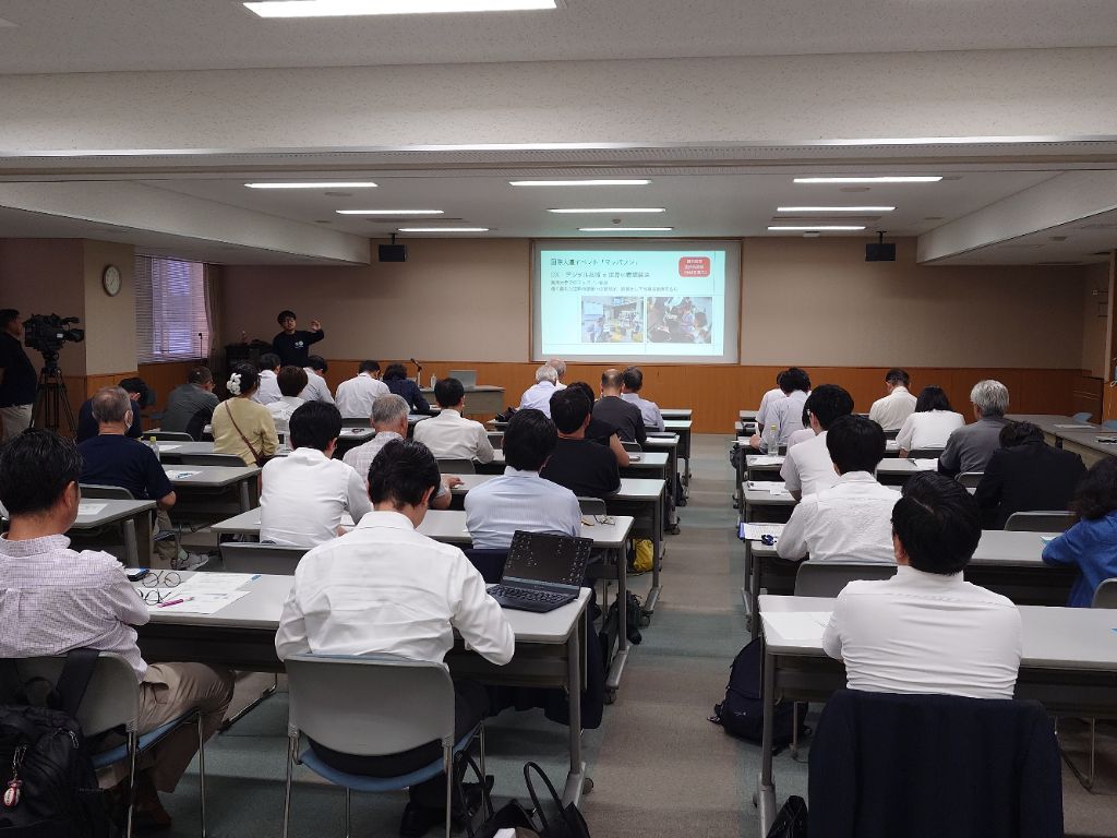 講演を行っている男性とそれを聞く参加者の写真