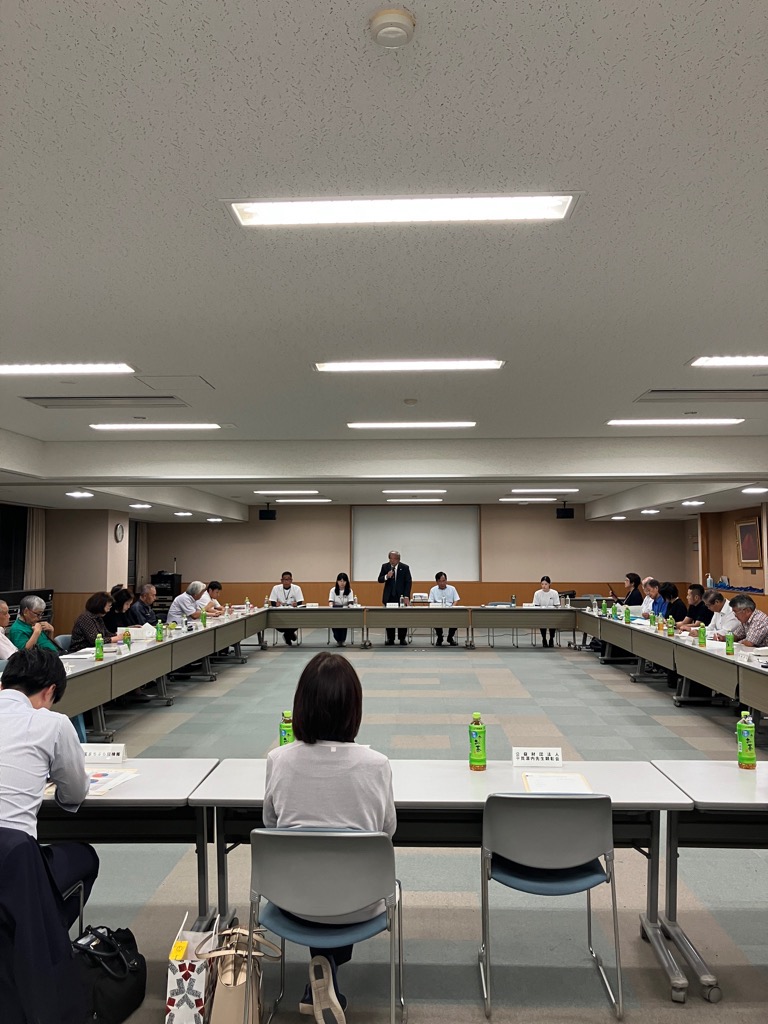 大きな会議室で机を囲んで会議をしている参加者たちの写真
