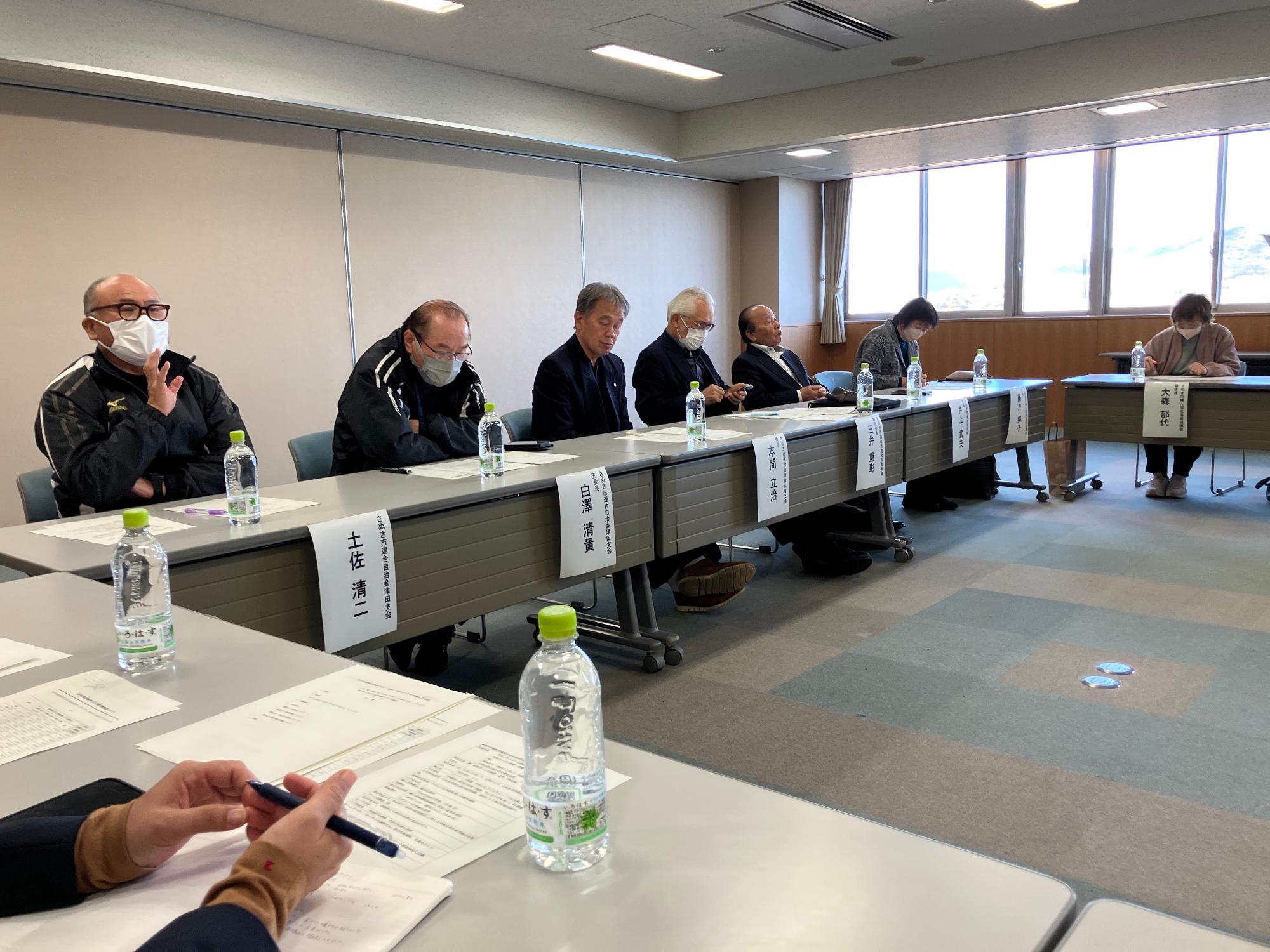 会議室にて意見を発表する男性とその話を聞いている参加者たちの写真