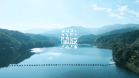 静かな湖を山々が囲む風景の中央に「ココロとからだの開放さぬき市」とタイトルロゴが入った写真