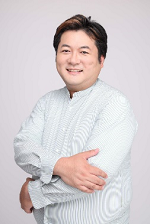 白い服を着た男性が腕を組んで微笑む写真