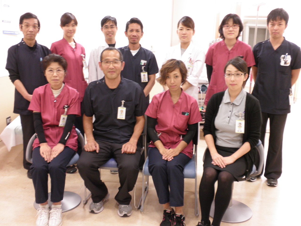 赤や紺のスクラブを着た人たちの集合写真
