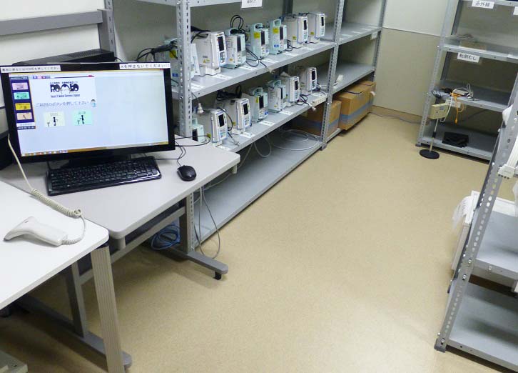 棚に並んだ機材とモニターが置かれた部屋の写真