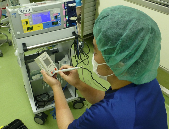 メディカルキャップを付けた人が手のひらサイズの機械を操作している写真