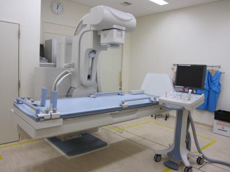 患者を横にしてX線撮影する装置とモニターが設置されている部屋の写真