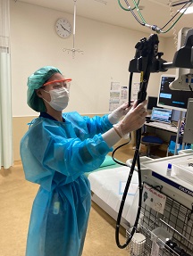 青のビニール製の防護服を着た人が機械を操作している写真