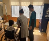 車椅子に座った人の対応をしている2人の写真