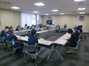 ロの字型に並べられた机で会議をしている人たちの写真