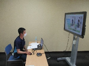 着席している人が大型のモニターを見ている写真