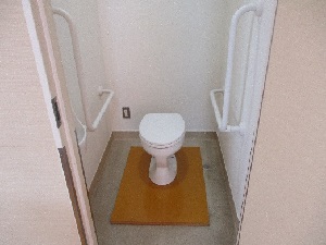 両脇の壁に手すりのついた白い便座の写真