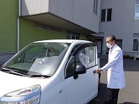 車の扉を開ける白衣姿の男性の写真