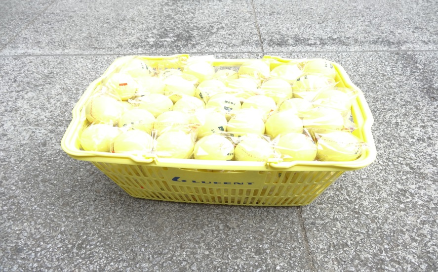 黄色いかごの上に入っている黄色いソフトテニスボールの写真