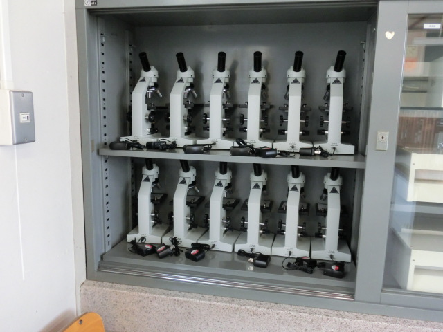 グレーの収納に並べられた白い顕微鏡の写真