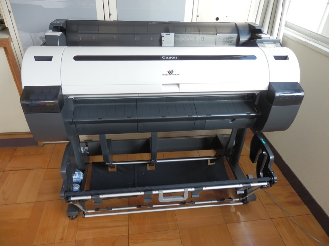 会議室のような場所に設置されたキャスター付きの大判プリンターの写真