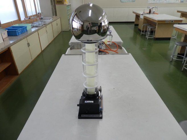 実験台の上に置かれた銀色が反射する静電気発生装置の写真