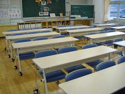 奥に黒板が設置されてて長机と椅子が整然と並んでいる写真
