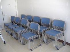 背もたれがある青い椅子が部屋の隅に重ねるように整理された写真