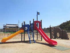 地面の上に赤とオレンジのすべり台が直角に二組ある写真