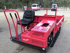 屋外に置かれた赤いキャタピラ運搬車の写真