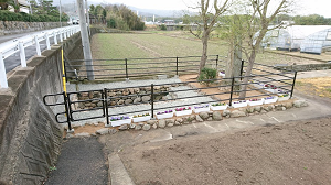 黒い柵に囲まれた中に木と石垣がある写真