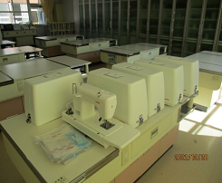 作業台の上に置かれたたくさんのミシンの写真