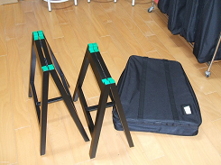 二脚の黒い脚立と四角い袋が置かれている写真